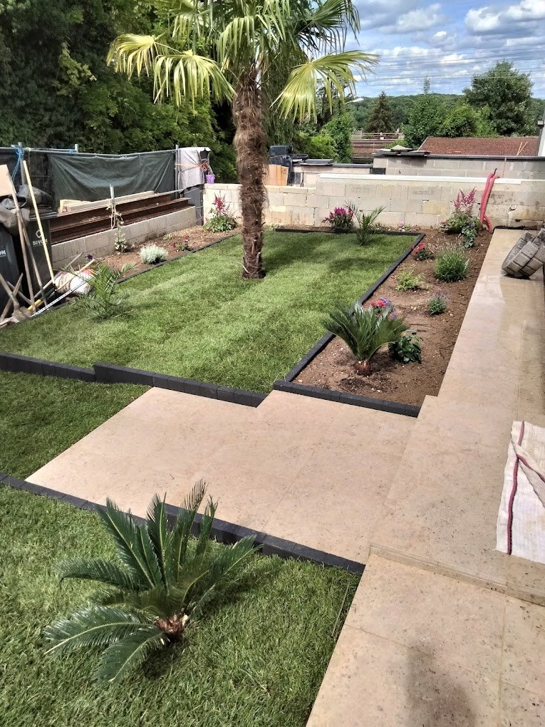 escalier pavé qui descend dans un jardin vert clôturé